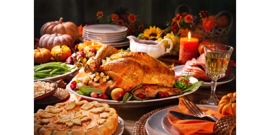 Image of table with candles, flowers, and loaded with traditional Thanksgiving dishes