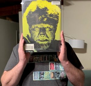 person holding a book cover with image of werewolf in front of face