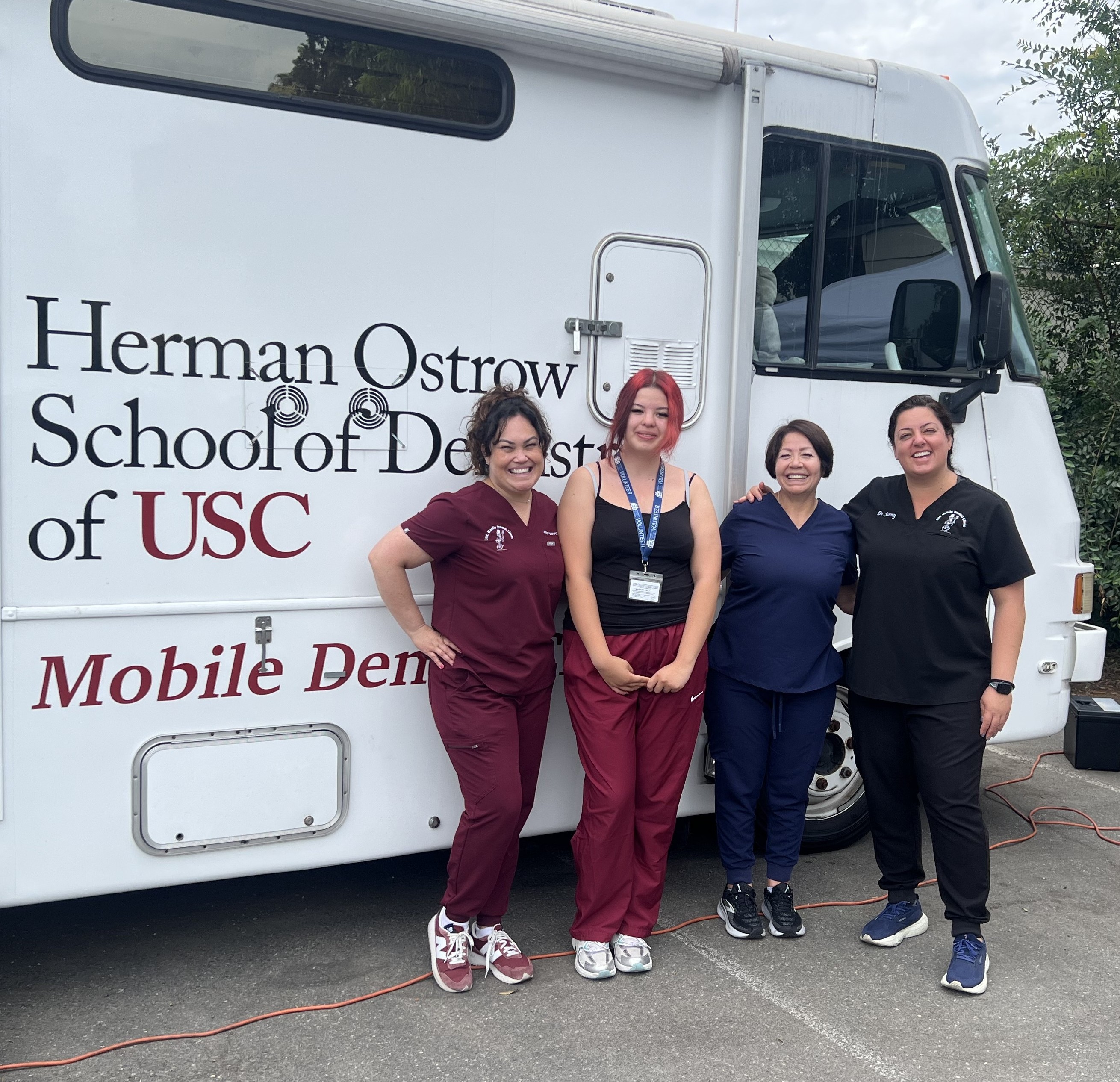Dental students from the USC Herman Ostrow School of Dentistry stand with a summer youth intern outside the USC Dental Van.