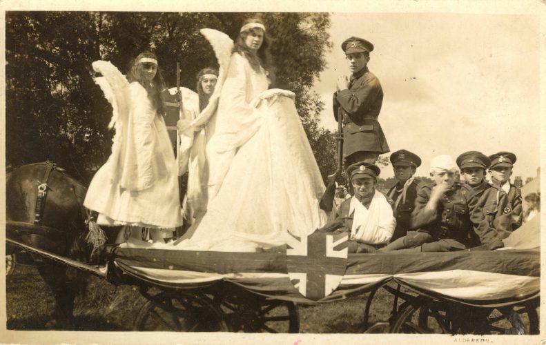 postcard-image-of-wwI-era-parade-float-with-women-dressed-as-angels-and-boys-in-military-uniform
